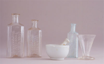 Apothecary bottles, mortar and pestle, and measuring cup from J. J. Klein drugstore (1845-1938) 